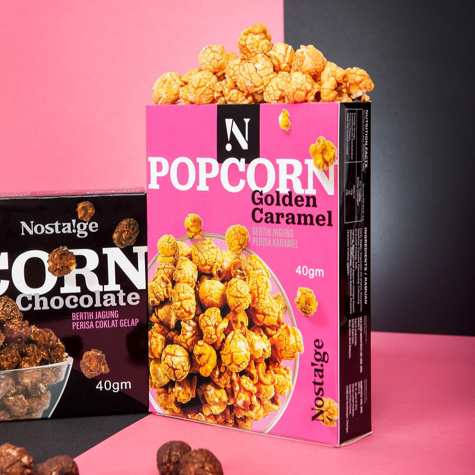 Pink box of Nostalgia popcorn with golden caramel flavor on a pink and black background