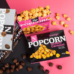 Nostalgia popcorn boxes with different flavors on a pink and black background