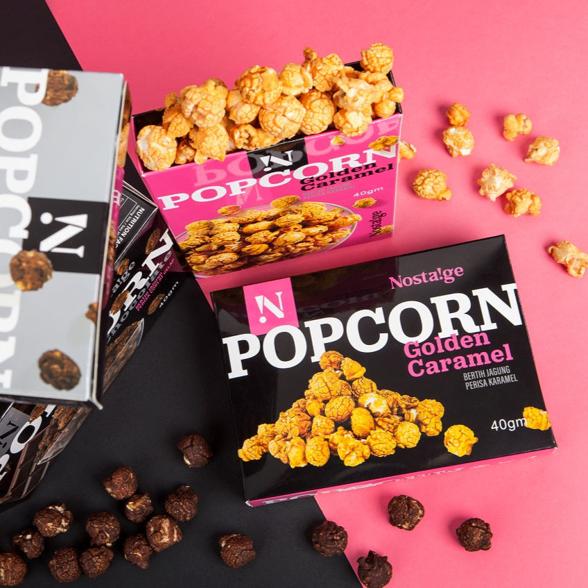 Nostalgia popcorn boxes with different flavors on a pink and black background