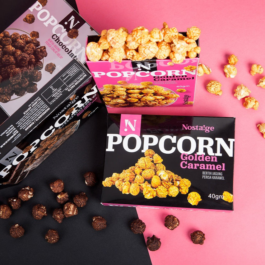 Nostalgia popcorn packages on a pink and black background with chocolate and caramel popcorn.