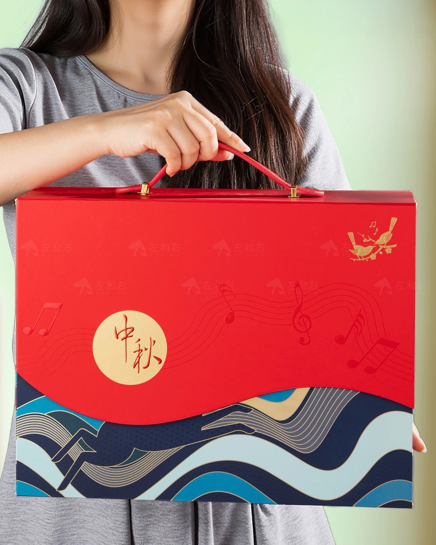 Person holding a red gift box with blue wave design and gold accents