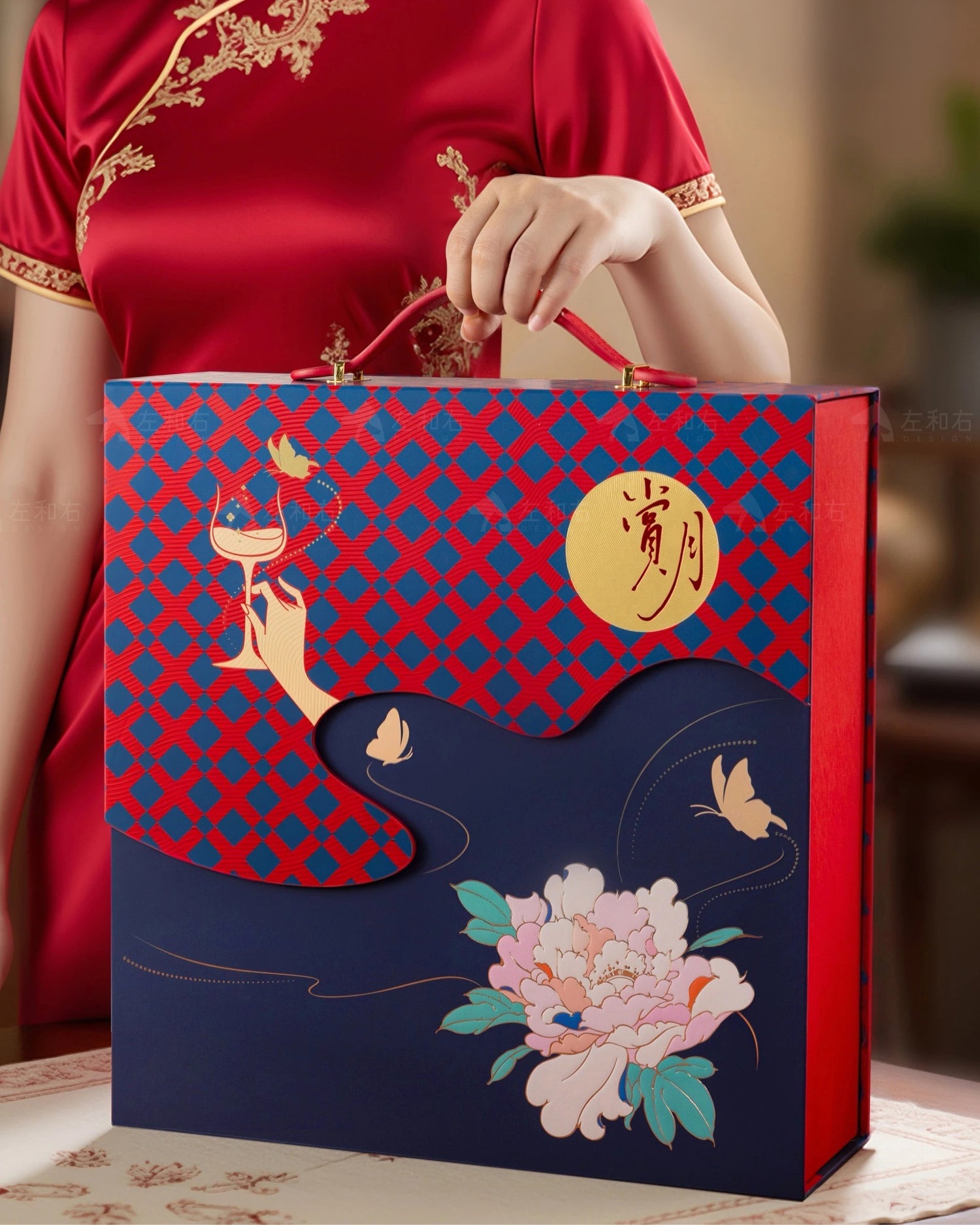 Person holding a decorative gift bag with floral and butterfly design, wearing a red traditional outfit.