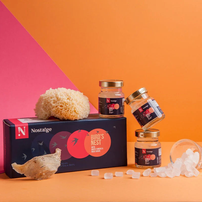 Jars of bird's nest and a box labeled 'Nostalgie' on an orange and pink background
