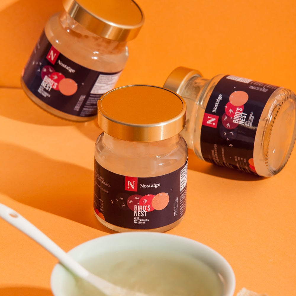 Three jars of Bird's Nest on an orange background with a bowl and spoon.
