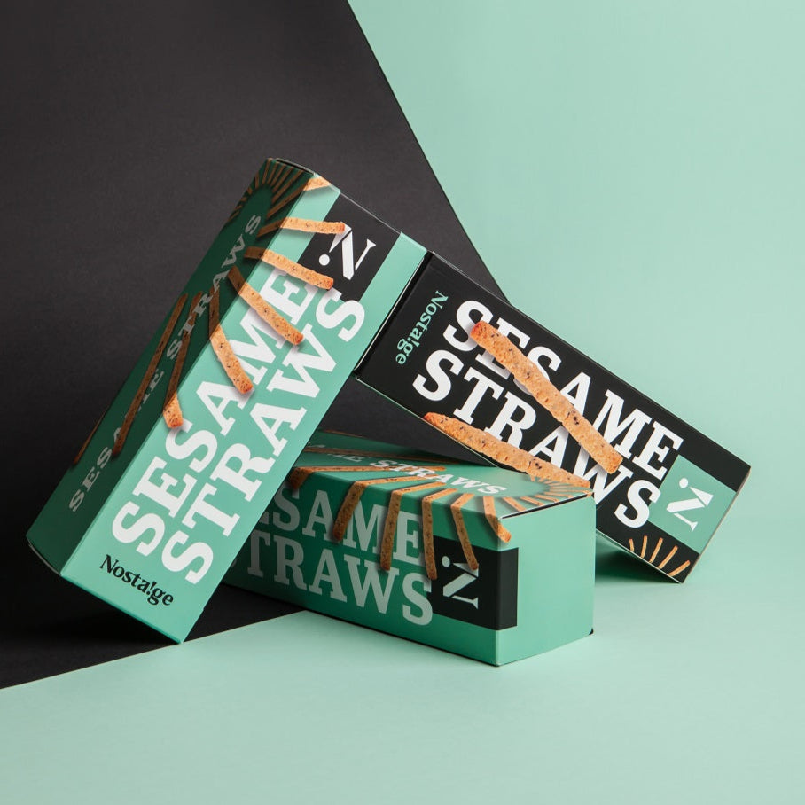 Three boxes of Nostalgia Sesame Straws on a green and black background