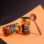 Two jars of honey with a wooden spoon on an orange and black background