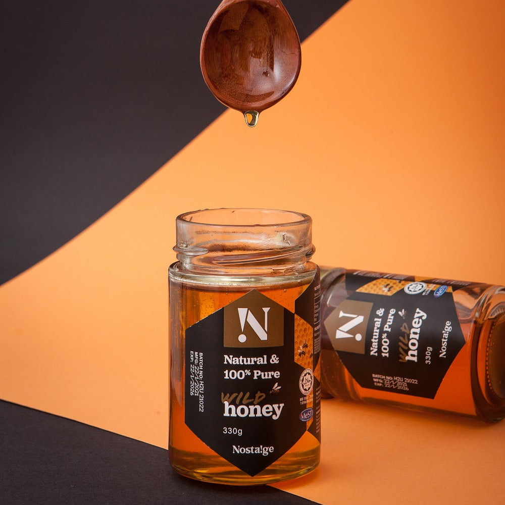 Jar of honey with a wooden spoon dripping honey on an orange and black background