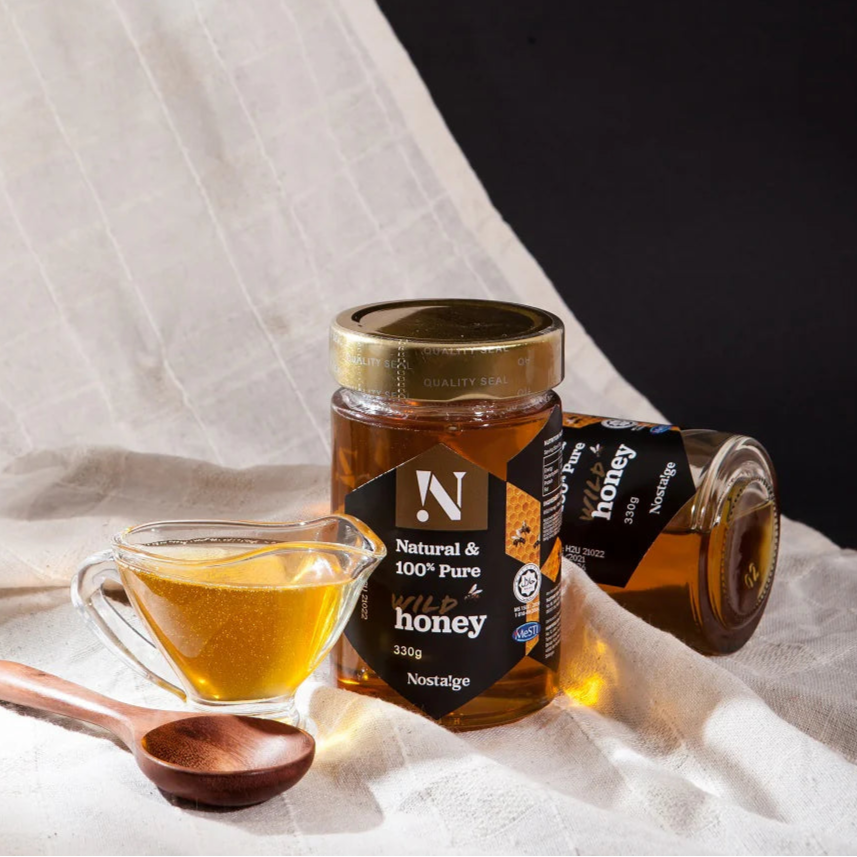 Jar of honey with a wooden spoon and small bowl on a light fabric background