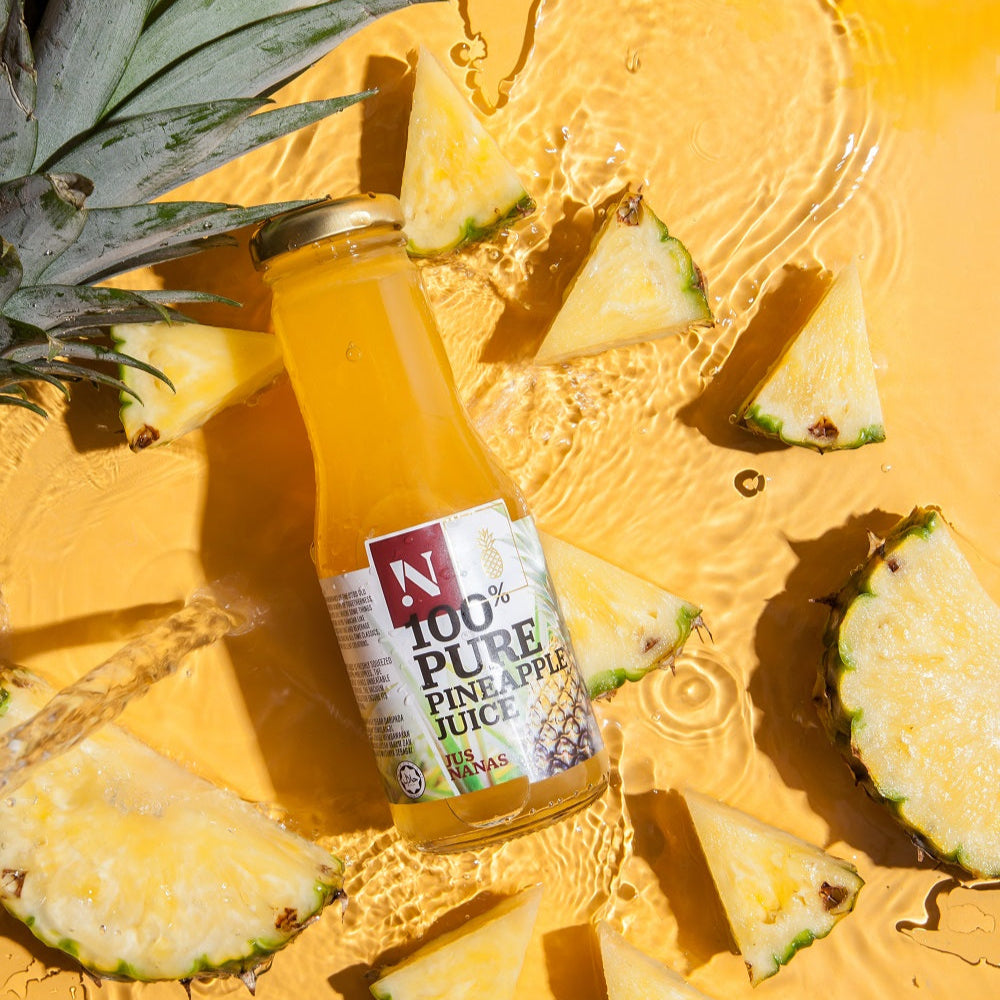 Bottle of 100% Pure Pineapple Juice with pineapple slices on a yellow background