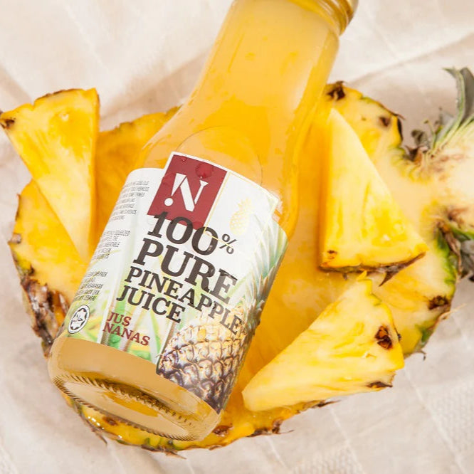 Pineapple juice bottle inside a halved pineapple on a white background