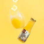 Bottle of pineapple juice with a glass on a yellow background