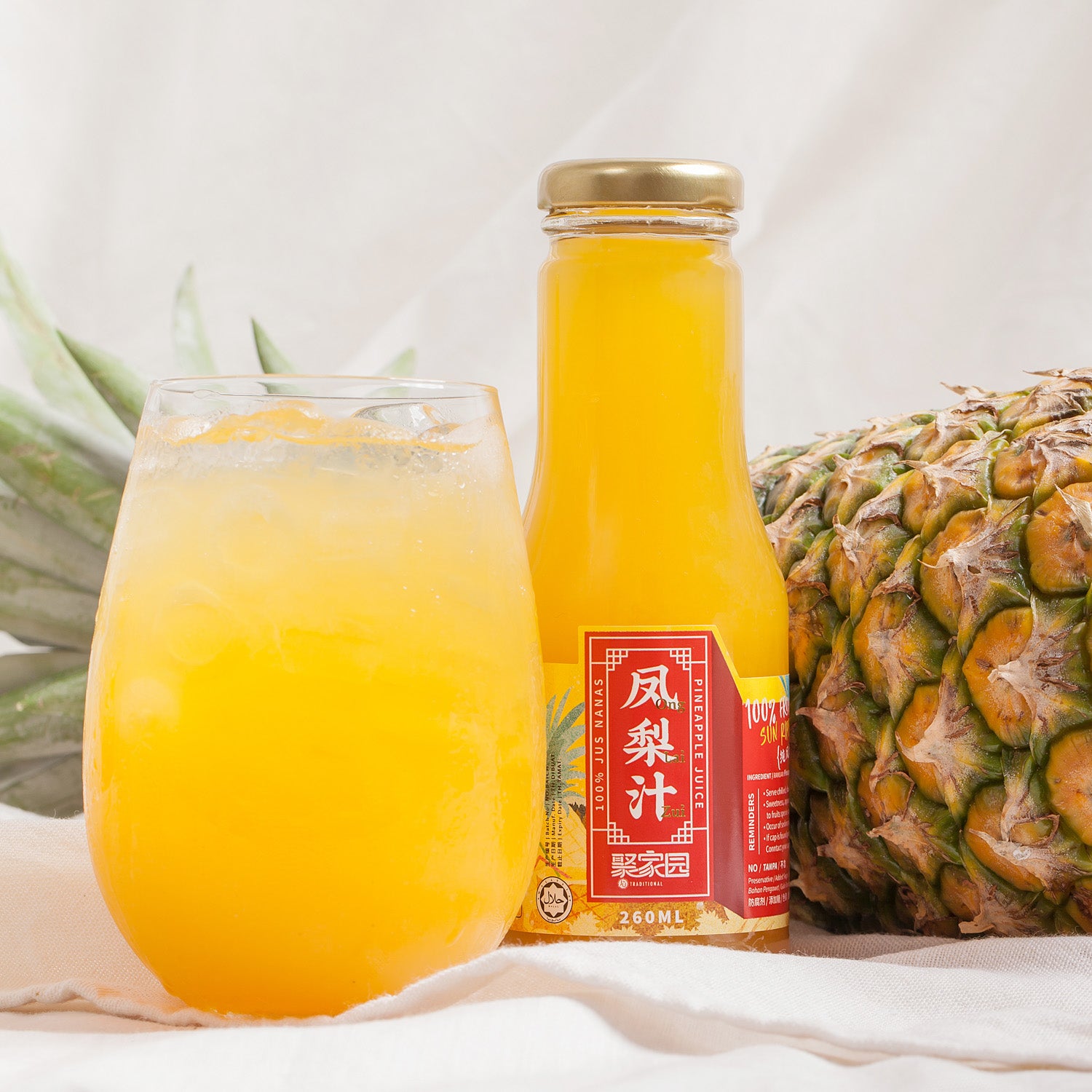 Pineapple juice bottle with a glass of juice and a pineapple on a light background